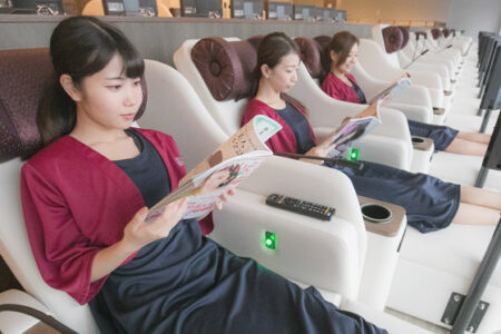 リクライナーで雑誌を読んで寛いでいる人の写真