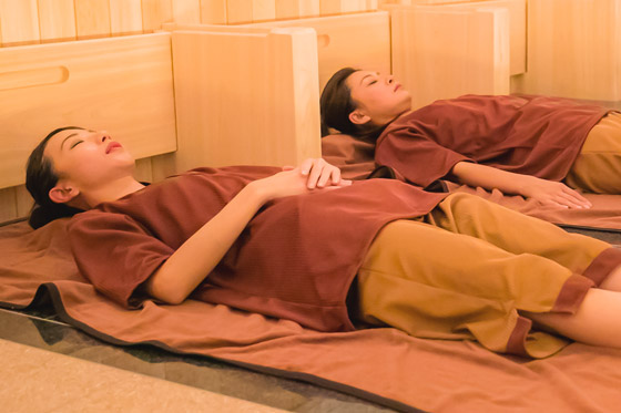 岩盤に仰向けで横たわり岩盤浴をする人の写真