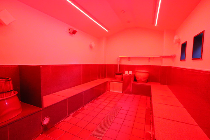 女性漢方薬草塩サウナ室内。赤色のコラーゲンライト